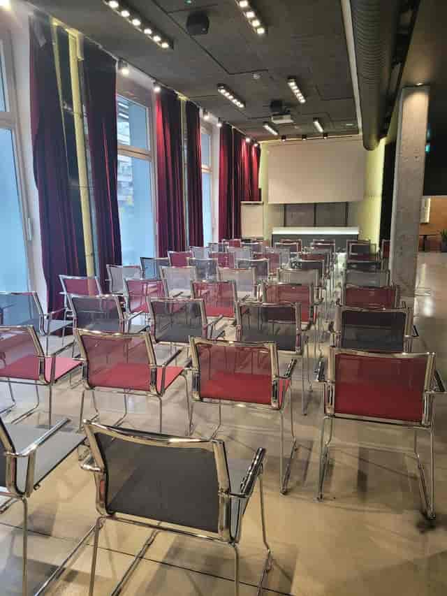 Theater room with mesh seating, natural light, and drapes for corporate events or presentations.