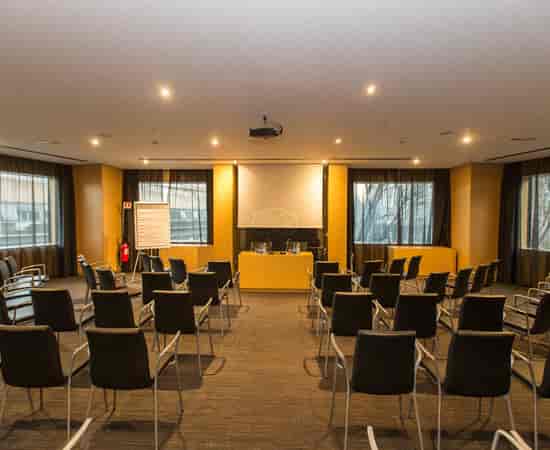 Theater-style meeting room at AC Hotel Milano with yellow accents for corporate events.