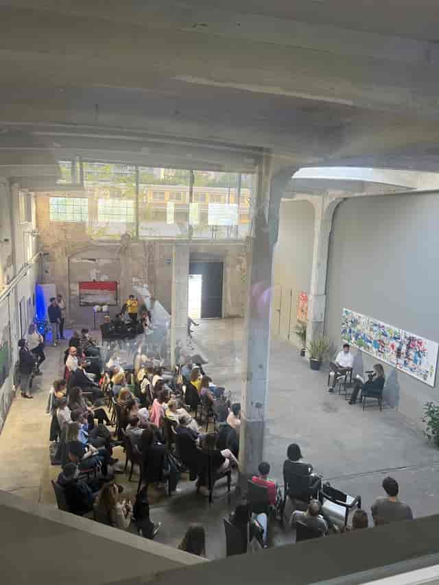 Industrial-chic panel discussion venue at Galleria LAMPO with exposed architecture.