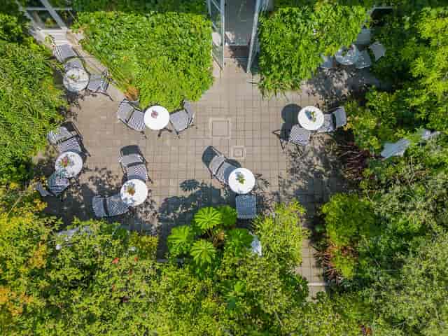 Garden House Milano outdoor networking space in a charming, lush garden setting.