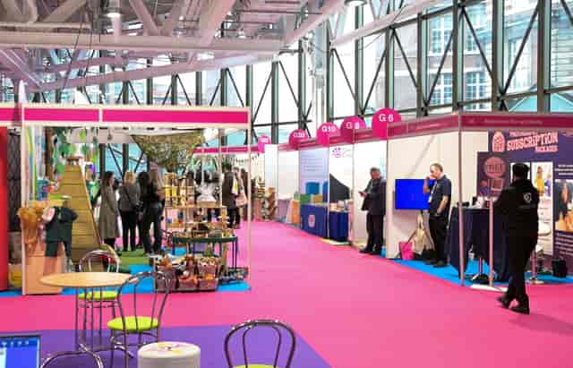 Vibrant exhibition space in West Hall, Olympia with colorful booths and networking opportunities.