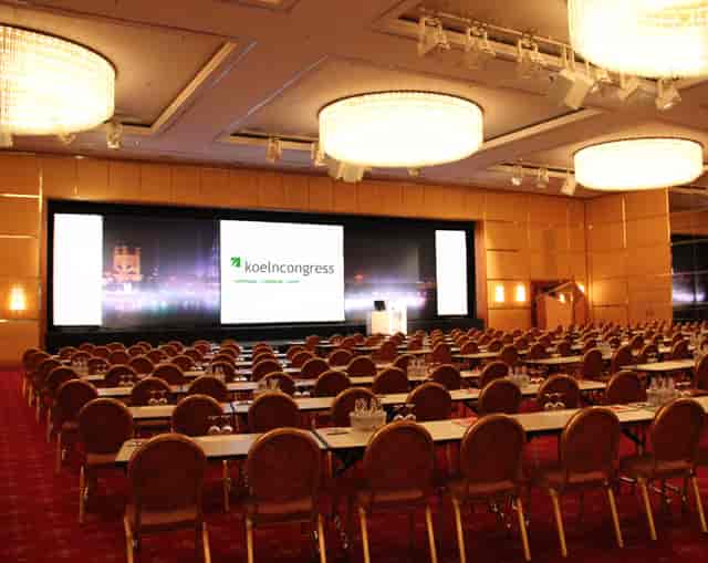 Congress Centrum plenary session with triple-screen AV stage and schoolroom seating for events.