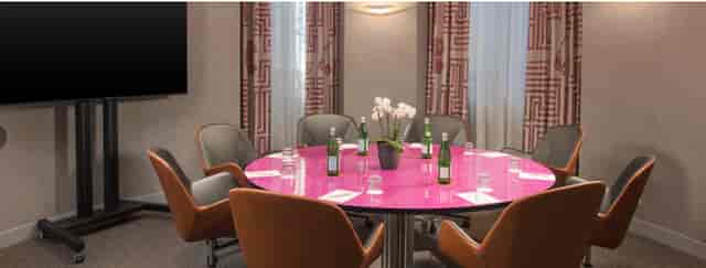 Modern meeting room with pink conference table, ideal for productive corporate events.
