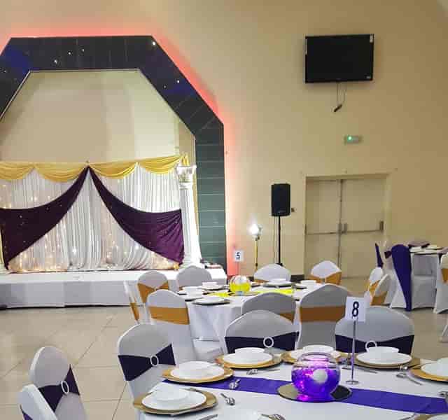 GMB Banqueting hall with round tables and LED stage lighting for wedding or corporate events.