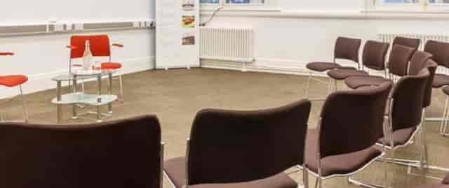 Minimalist meeting space in Friends' Meeting House with red chair for workshops.
