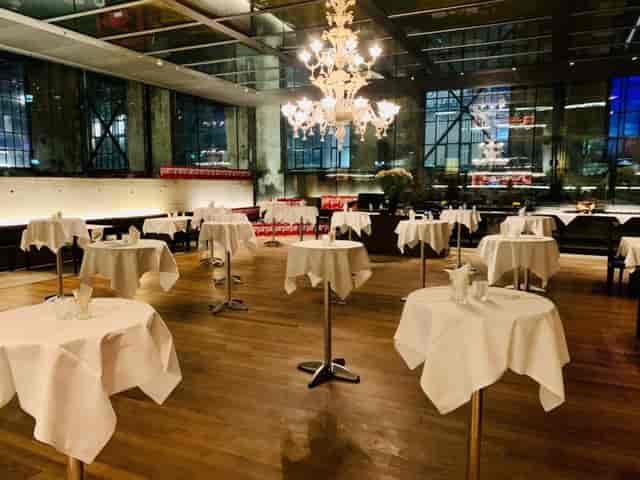 Industrial-chic restaurant reception with large chandelier for wedding and corporate events.