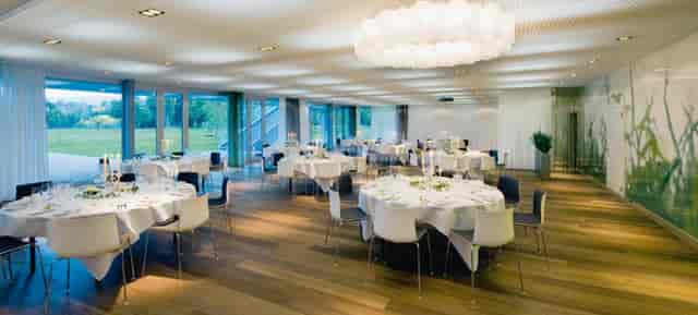 Modern banquet hall with glass walls for high-end corporate dinners and upscale social events.