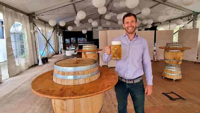 Oktoberfest rustic corporate networking event with barrel tables and tent venue.