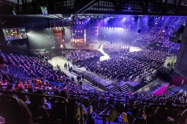 Hallenstadion split-stage general session setup with atmospheric lighting for corporate events.
