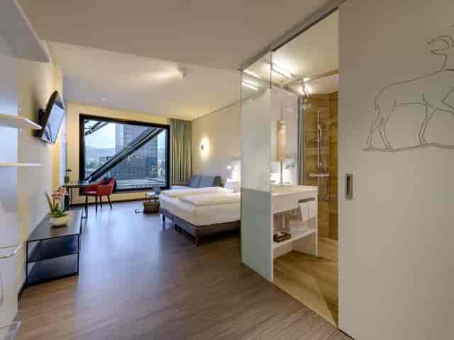 Modern twin-bed hotel room at Mercure Zurich City with workspace for business travel events.