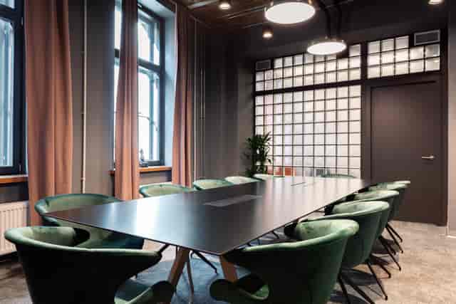 Emerald velvet boardroom with industrial accents for executive strategy and small-group meetings.