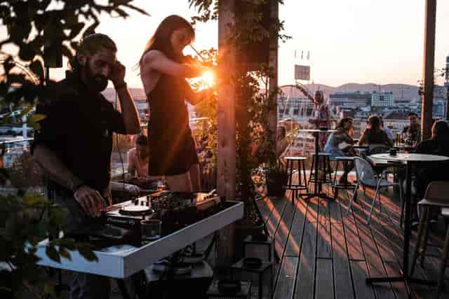 Sunset rooftop reception at Zoku Vienna with live DJ and violinist entertainment.