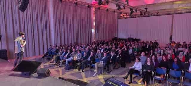 Full capacity theater-style breakout session with professional AV lighting for corporate events.