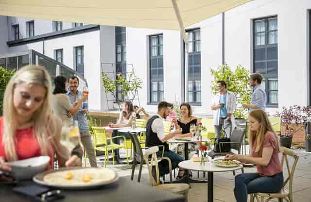 Casual outdoor networking mixer with bistro seating at ARCOTEL Donauzentrum Wien event venue.