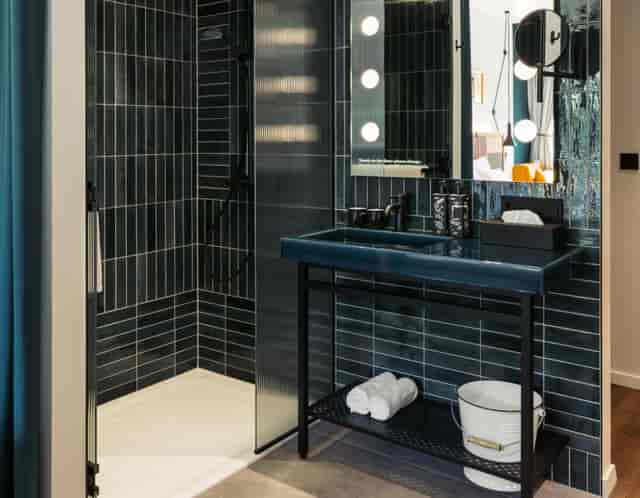 Modern boutique hotel bathroom with dark-tiled decor for premium event room blocks.