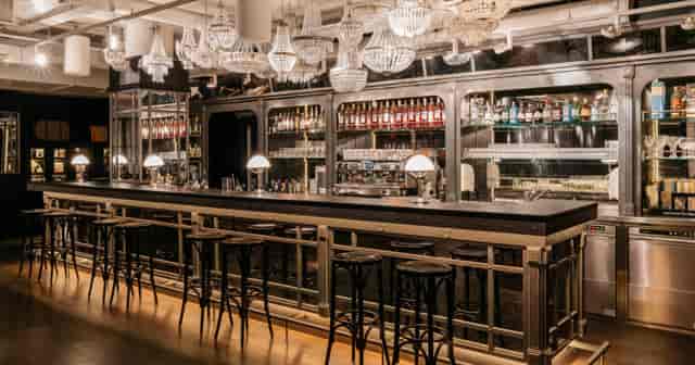 Industrial-chic Ruby Lissi hotel bar with crystal chandelier for corporate networking events.
