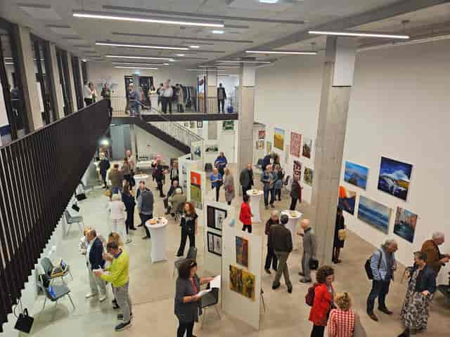 Networking reception in F23 gallery featuring high-top tables for event flow and display walls.