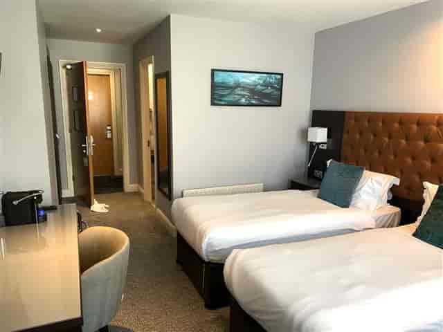 Twin guest room at Grand Canal Hotel with workstation, ideal for corporate travel and event lodging.
