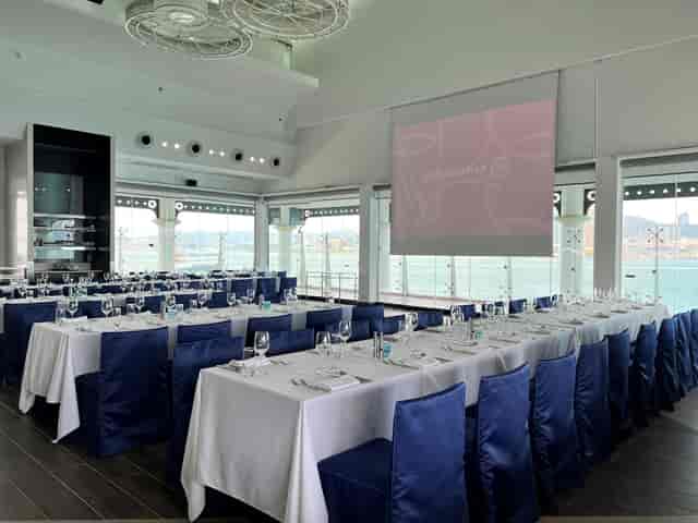 Waterfront event space in Hong Kong with formal long-table seating for corporate dining and events.