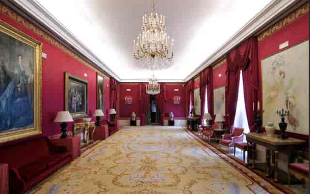 Elegant red-walled venue with chandeliers for upscale meetings and events at Teatro Real.