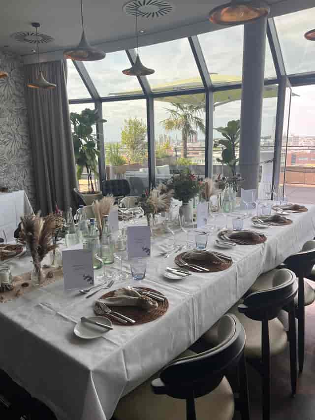 Wasserturm Hotel rooftop dining: elegant executive corporate luncheon setup with city views.