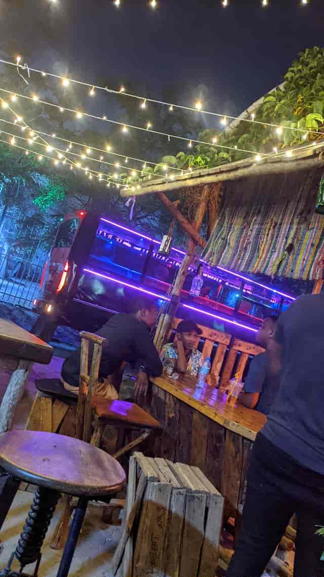 Rustic open-air bar and grill with neon party bus backdrop for social networking events.