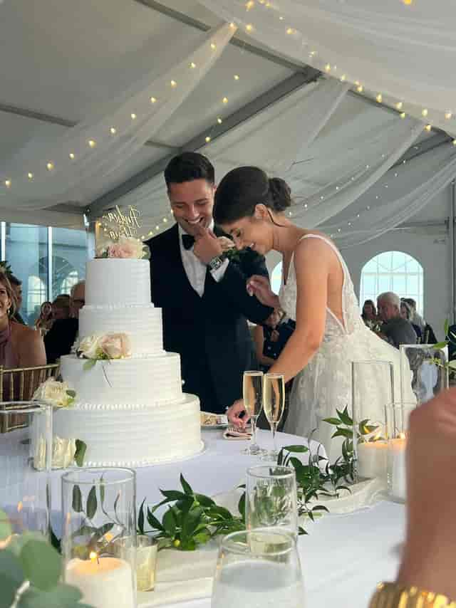 Tented wedding reception at The Penthouse with string lighting and cake service.