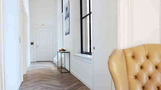 Minimalist Hotel Kop van Zuid suite with herringbone floors for event registration or VIP lounge.