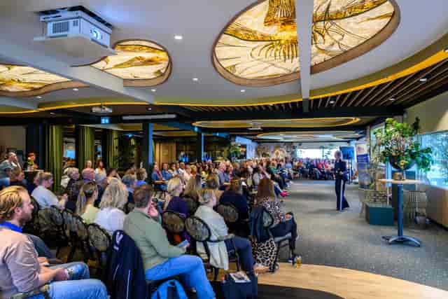Theater-style session in biophilic Lommerrijk event space with creative ceiling design.