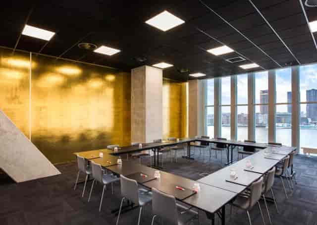 Modern meeting room in nhow Rotterdam with gold-tinted wall for professional events.