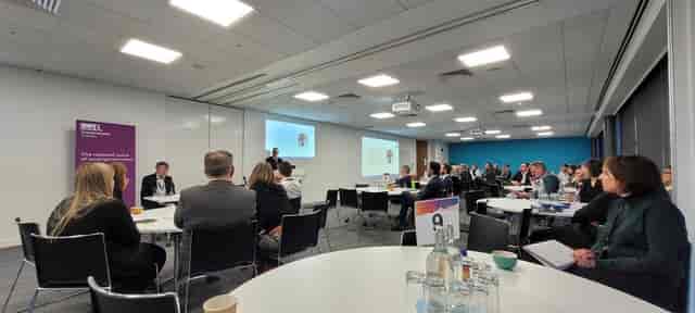 Corporate conference round-table seating with professional stage and AV setup for business events.