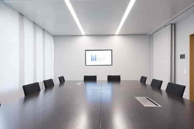 Minimalist executive boardroom with integrated tech for corporate strategy meetings and workshops.