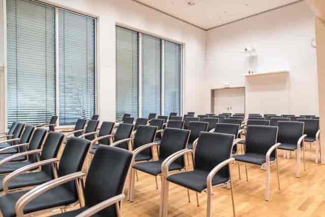 Theater-style seating in minimalist Münchner Saal conference venue for lectures and presentations.