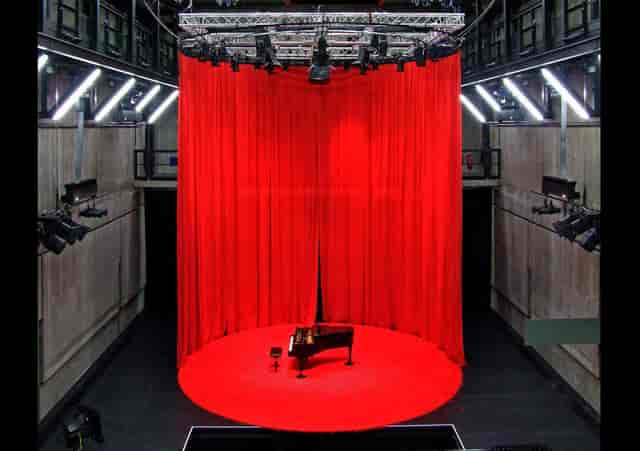 Grand piano on circular riser in Reaktorhalle, perfect for theatrical performances or live concerts.
