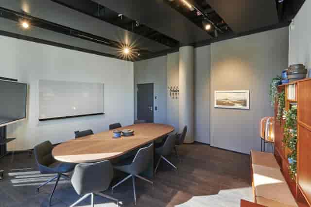 Contemporary breakout room with oval wooden table for hybrid meetings and team collaboration.