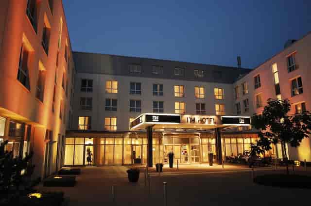 NH München Ost conference hotel exterior at dusk for corporate meetings and business training.