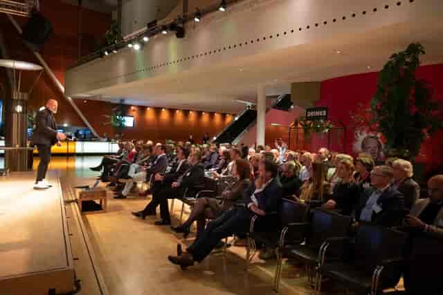 Corporate plenary session at Rhine Foyer New Luxor theater with spotlighted stage for events.