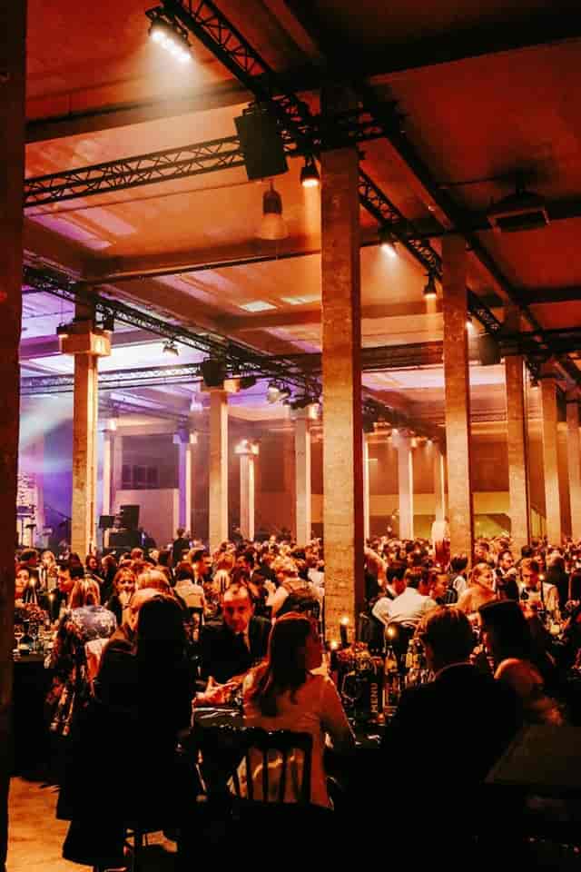 Gala dinner in industrial-chic venue with architectural columns, elegant corporate event lighting.