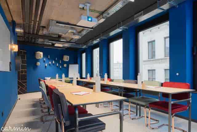 Modern industrial meeting room with blue walls, ideal for corporate workshops and training sessions.