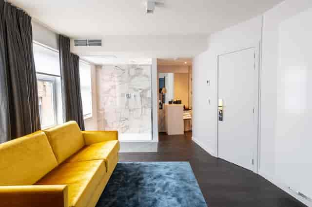 Modern hotel suite with vibrant accent sofa for luxury bleisure and VIP accommodation.