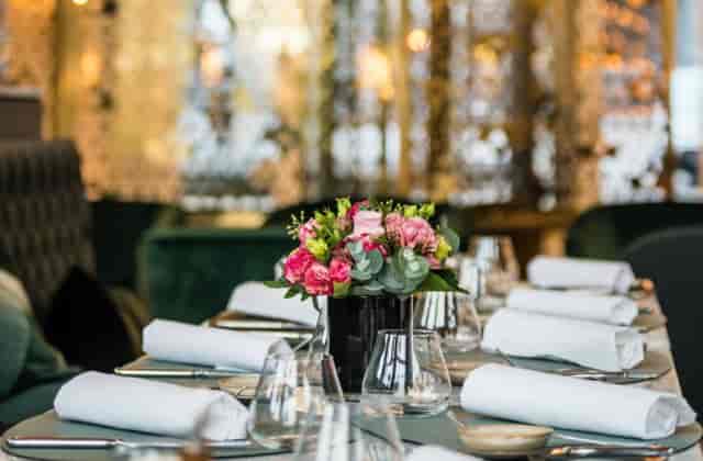 Upscale cocktail bar table setting with floral centerpiece for boutique dinner or social event.