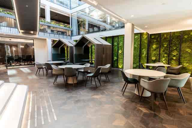 Biophilic corporate breakout area with privacy pods for networking and professional conferences.