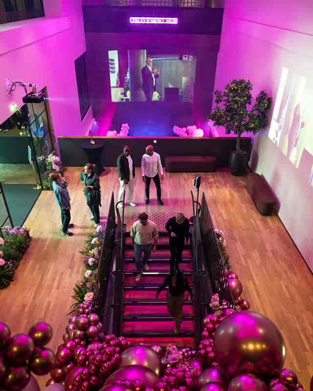 Modern Oslo Event Hub foyer with pink lighting and grand staircase for corporate events and galas.