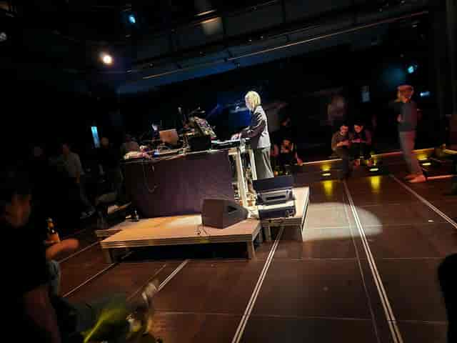 Technical rehearsal in Black Box Gasteig with cluttered AV equipment and stage lighting.