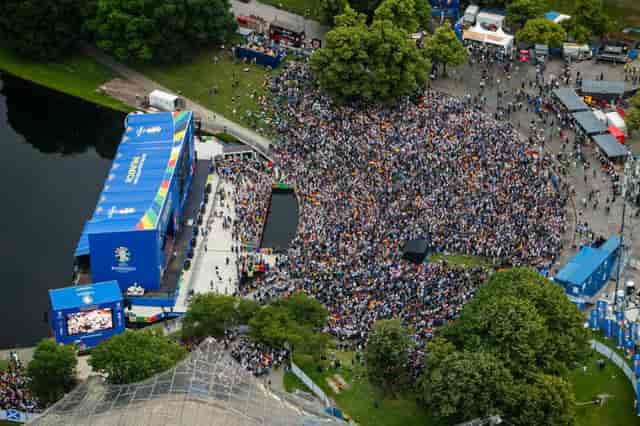 Outdoor public viewing fan zone by water for live sports and event screening.
