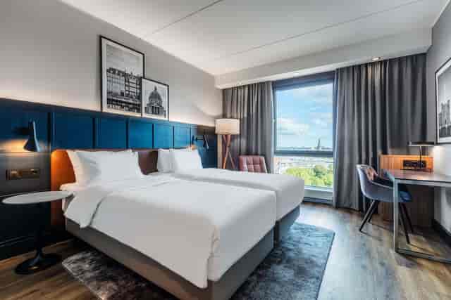 Modern twin hotel room with workspace for corporate conferences and business meetings.