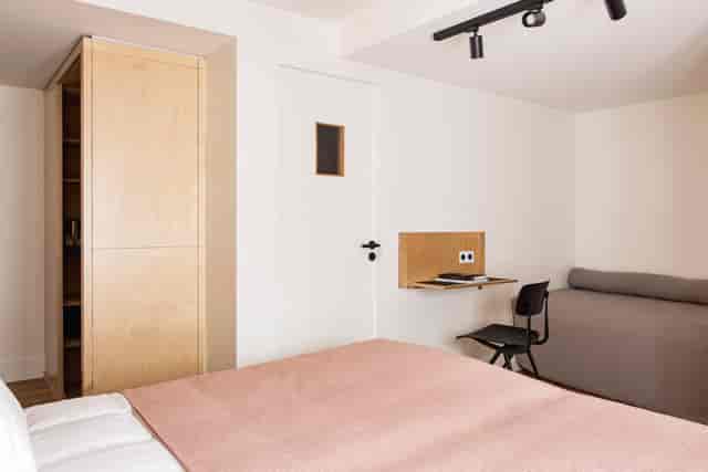 Minimalist micro-hotel room with workspace for business travel and urban event accommodation.