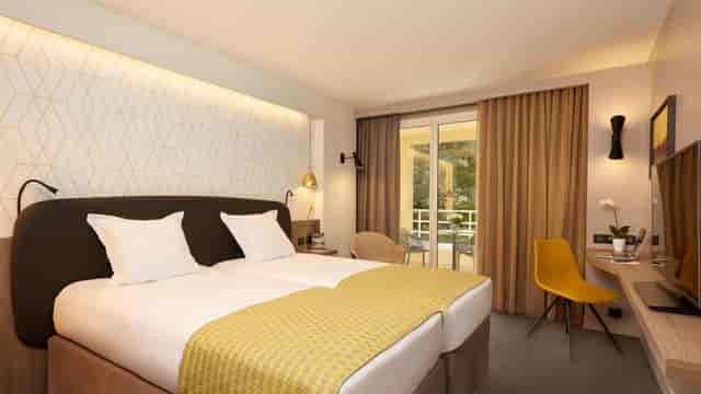 Twin-bedded hotel suite with workspace and balcony for business travel and corporate conferences.