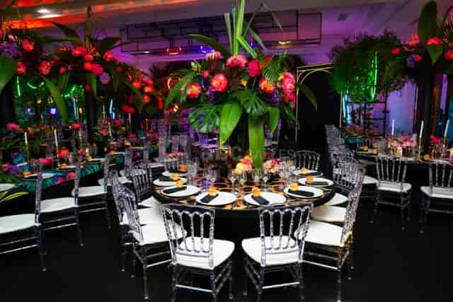 Tropical gala at Le Salon Toffoli with neon lighting and floral centerpieces for event planning.