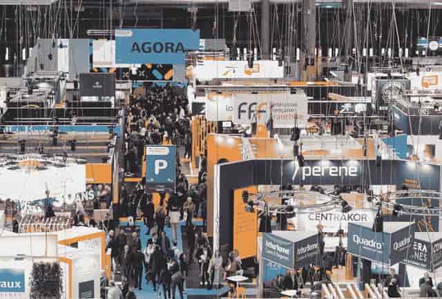 Bustling Franchise Expo Paris trade show floor with overhead signage and complex rigging.